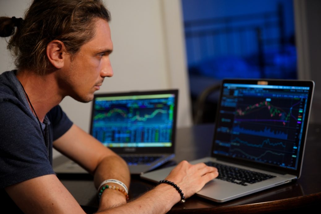 man looking at stock market on laptop