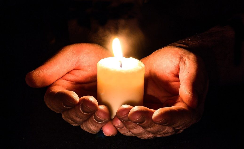 hands holding a lit candle