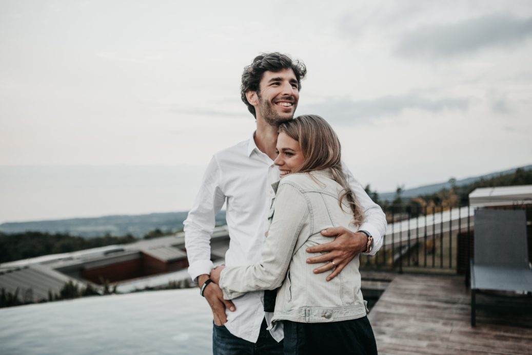 happy couple on gray beach hugging