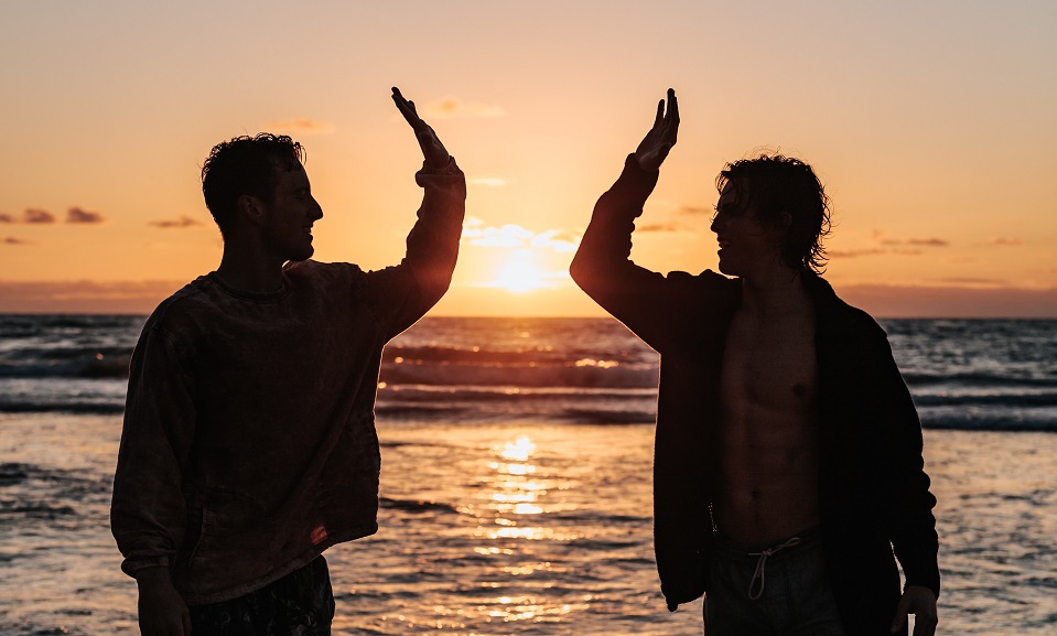 two men on beach sunset high five