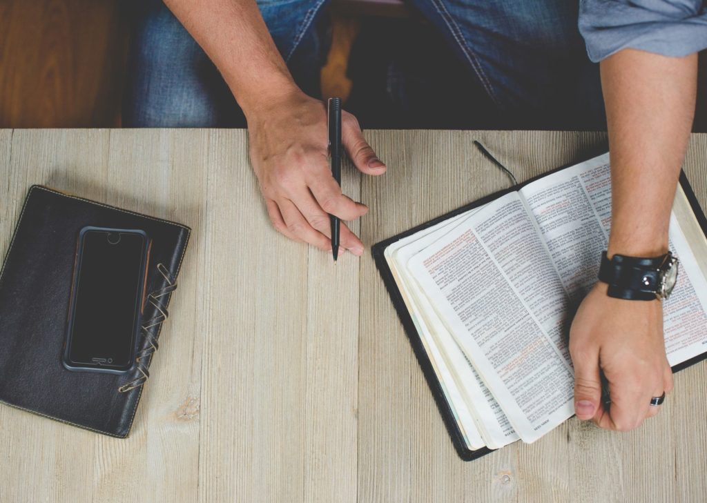 man holding bible and a pen close up