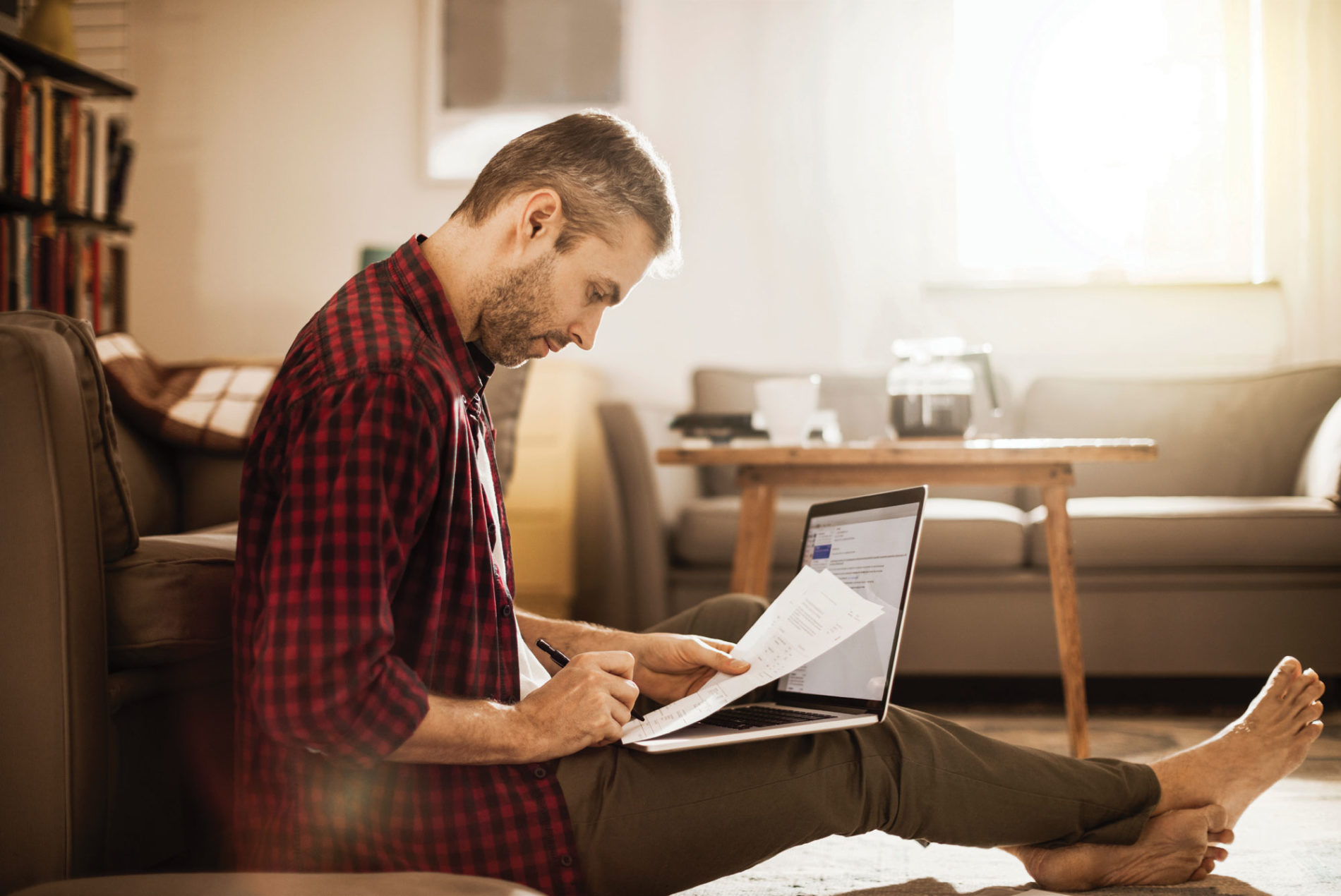 man using a laptop and marking a paper