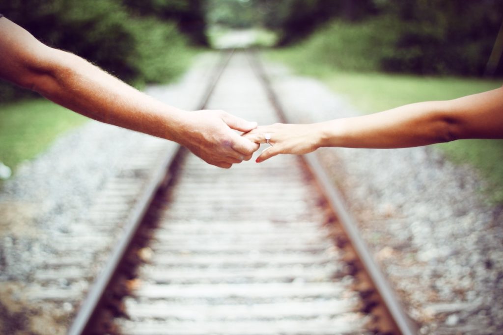hands holding over train tracks