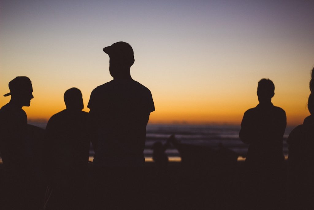 guys standing in sunset in front of lake