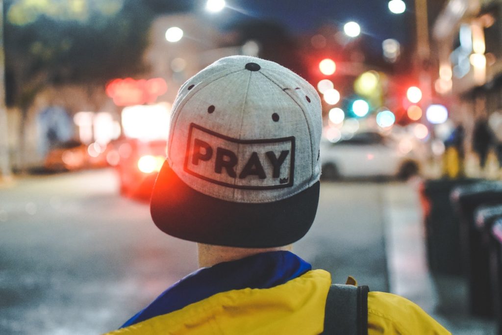 pray on snapback backwards on head background is street