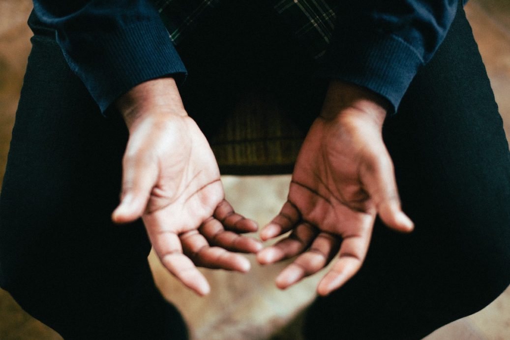 man with his hands out praying