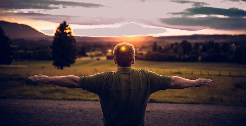 man with arms outstretched looking at sunrise
