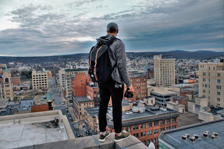 man on top of building looking at city with camera