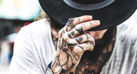man with tattooed hand tipping hat