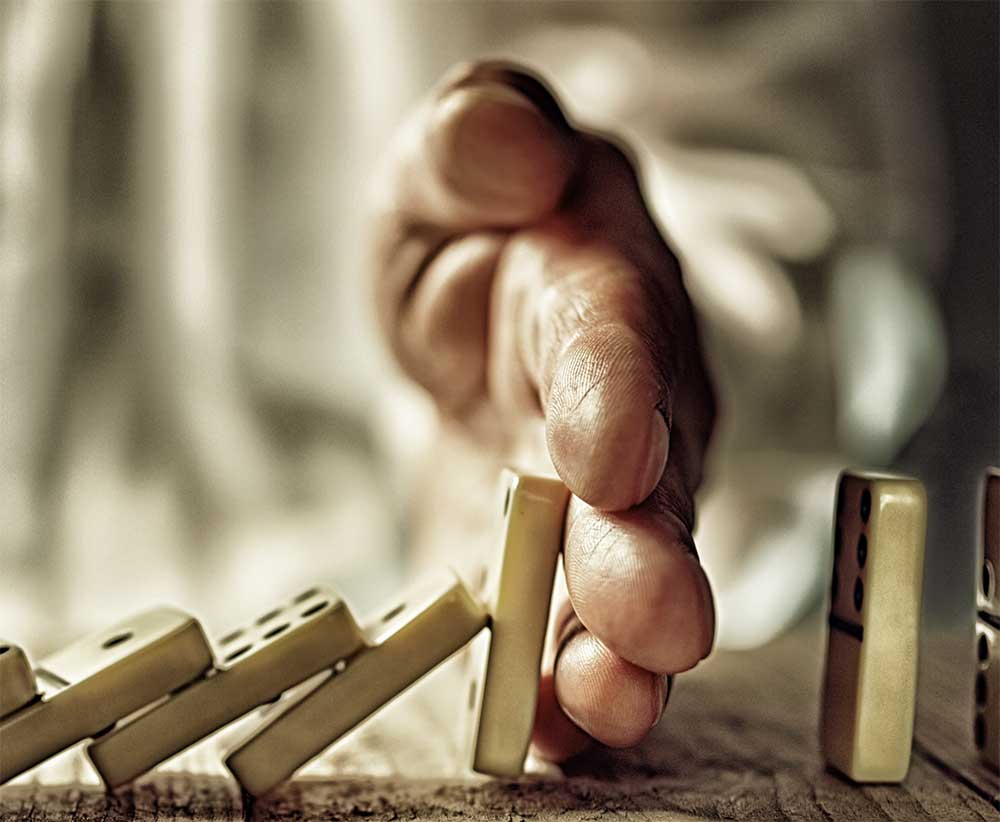 hand stopping falling dominoes