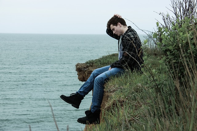 man sitting on a ocean side cliff