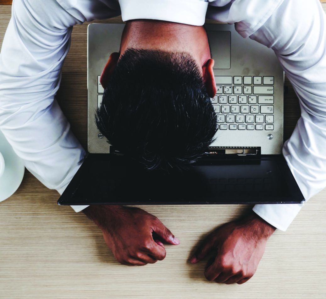 man hitting his head on laptop