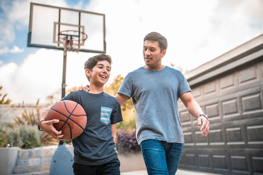 dad and son talking in driveway with basketball