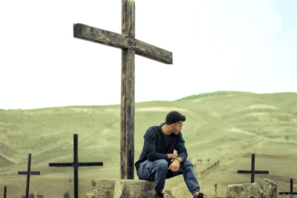 man sitting at the foot of the cross