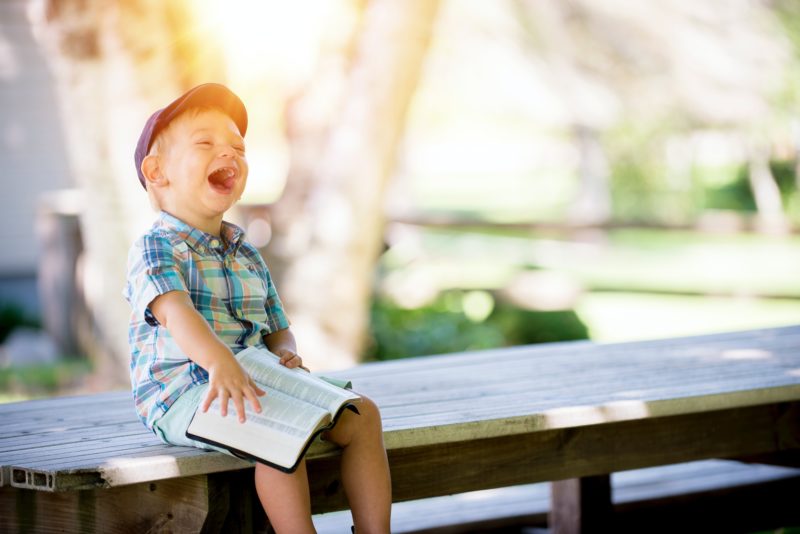 child joyfully laughing holding Bible