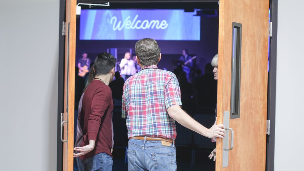 man going to church sanctuary with big welcome sign