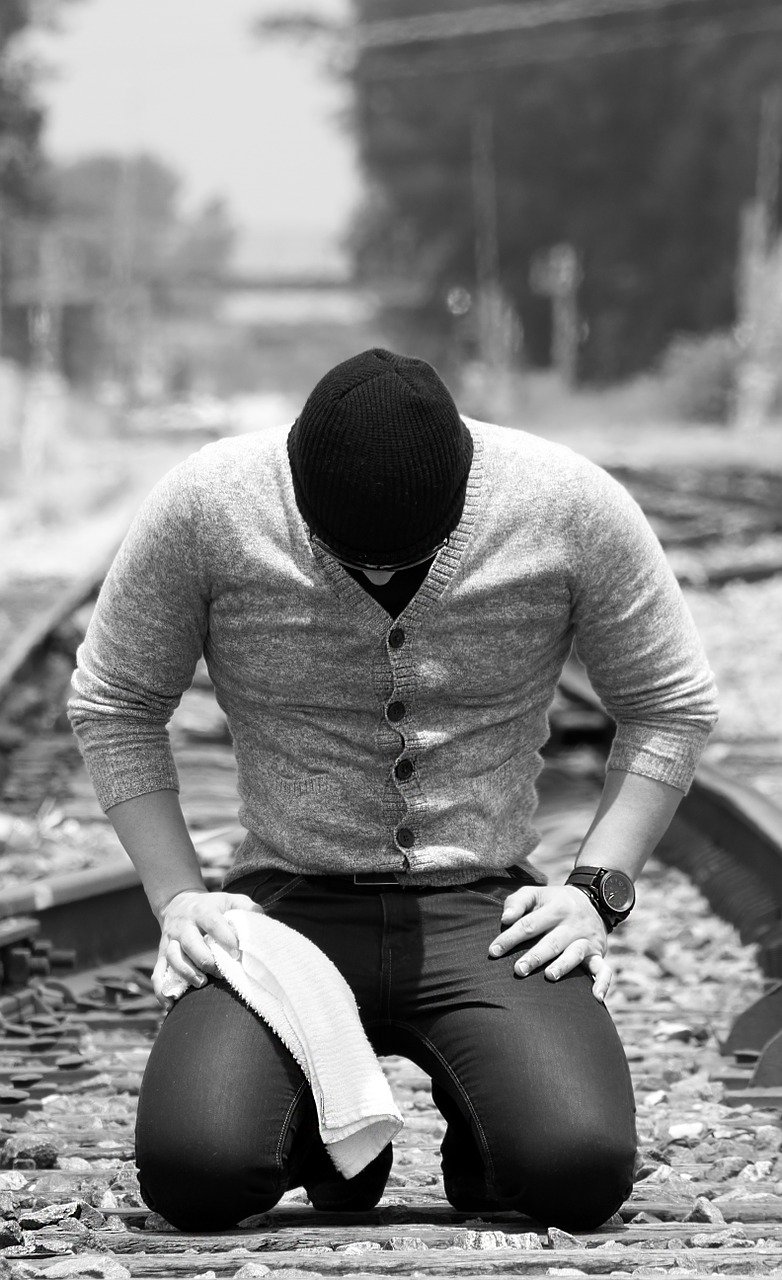 man praying in middle of train tracks