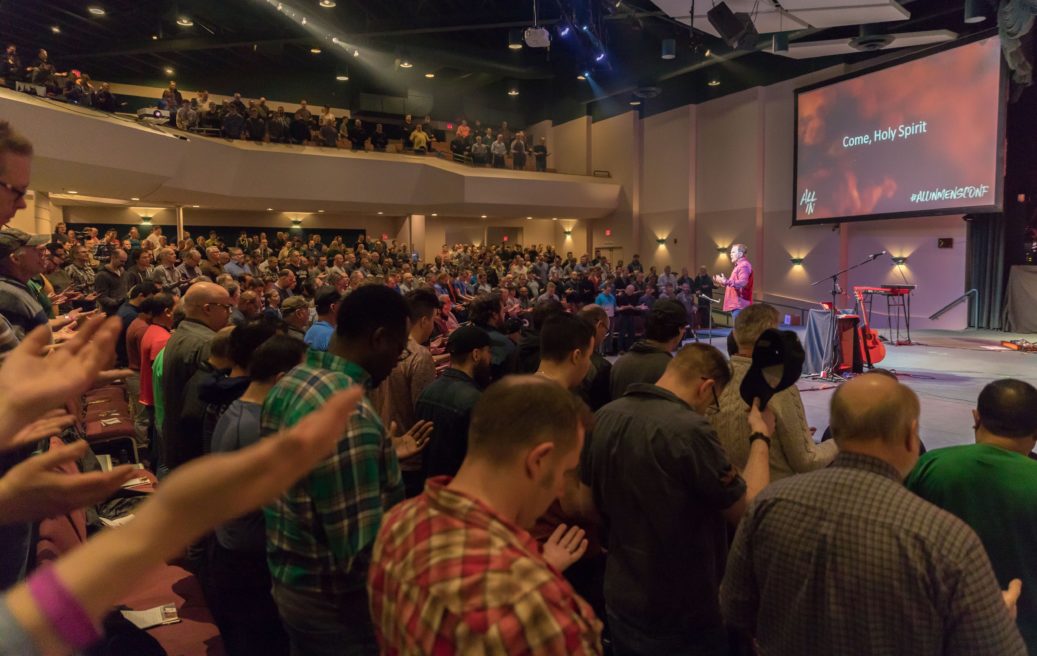 hundreds of men praying together in a church