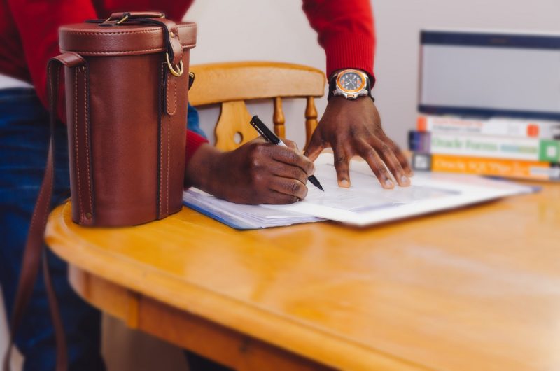 man making notes at kitchen table with leather bag